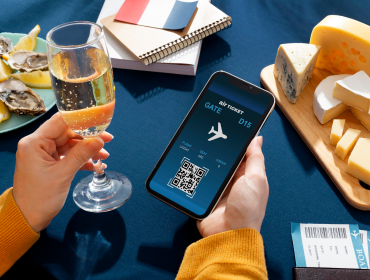 AI-Powered Travel & Hospitality Solutions Person holding wine and smartphone displaying digital boarding pass at dining table
